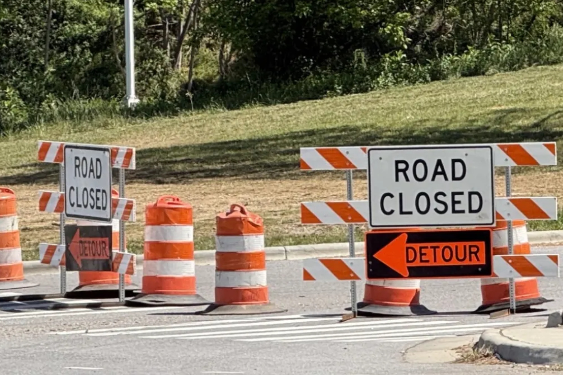Road closed signs and orange traffic barriers blocking the street ahead