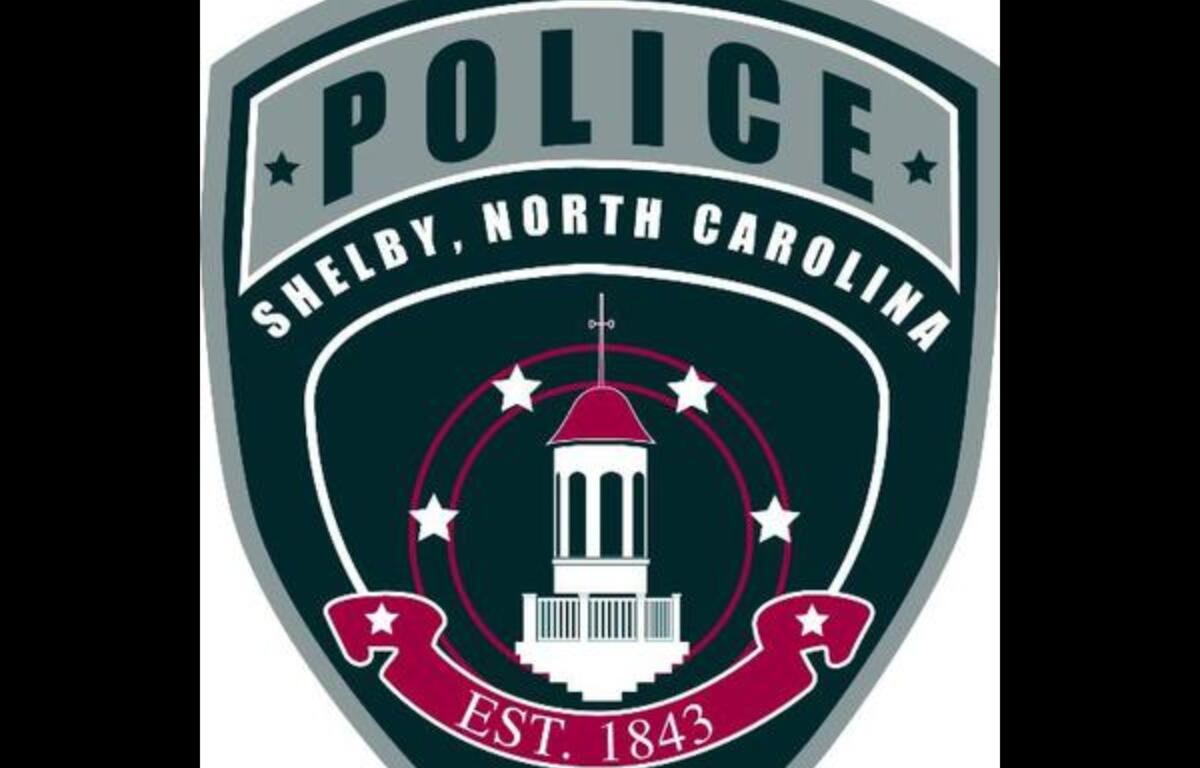 Shield-shaped police emblem for Shelby, North Carolina, with a central white courthouse tower, stars, and EST. 1843 text