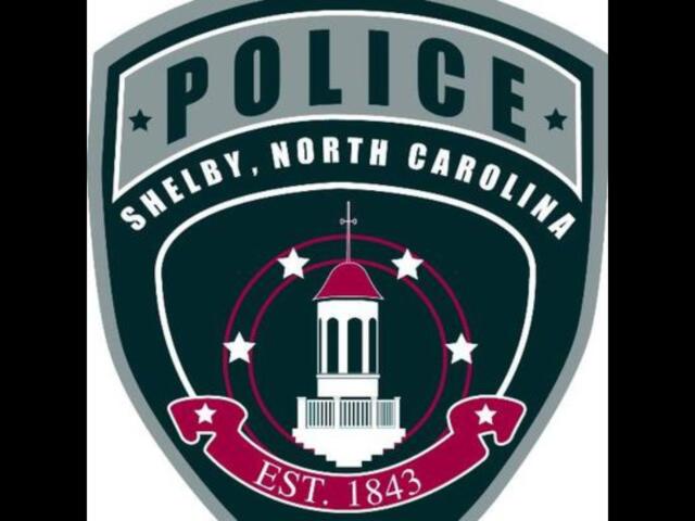 Shield-shaped police emblem for Shelby, North Carolina, with a central white courthouse tower, stars, and EST. 1843 text
