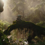 Grogu (Baby Yoda) statue sits on a mossy log in a sunlit, misty forest.