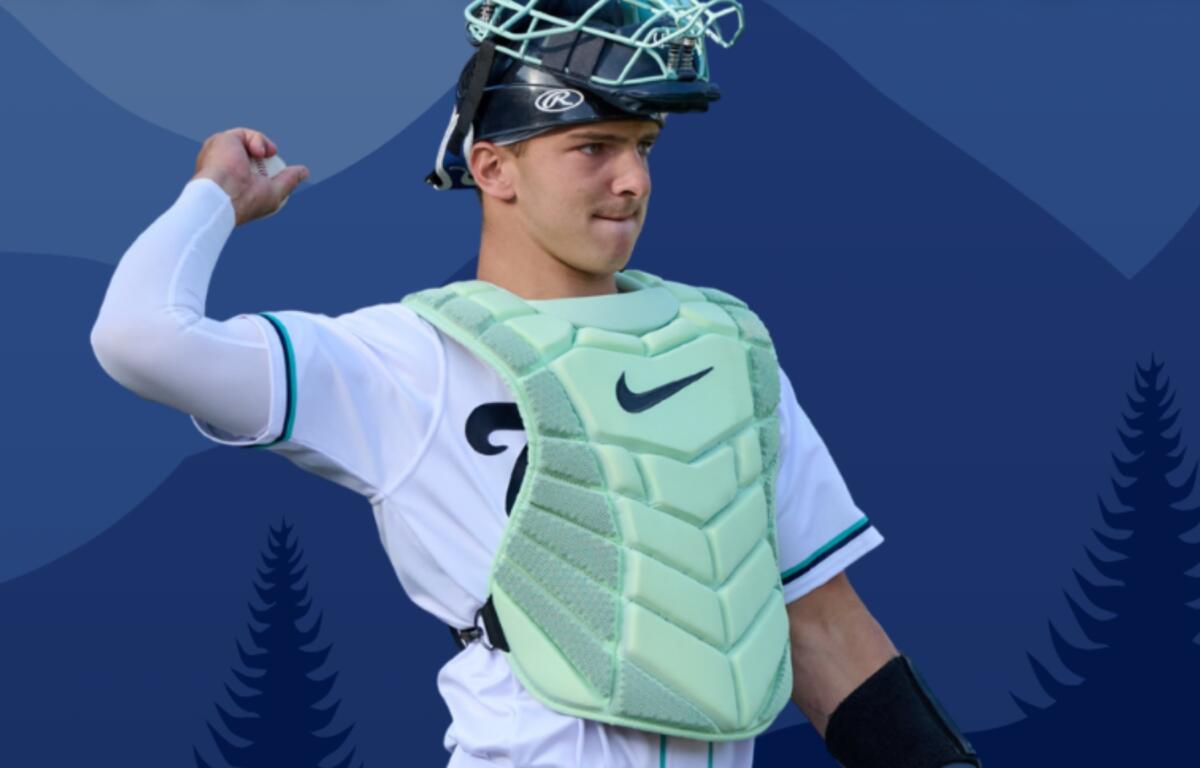 Baseball catcher in light mint-green chest protector and mask, mid-throw against a blue geometric backdrop.