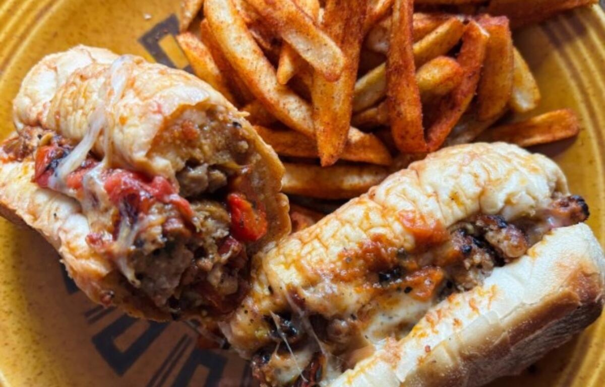 Plate with two stuffed chicken drumsticks with melted cheese and peppers, paired with seasoned French fries on a yellow plate.
