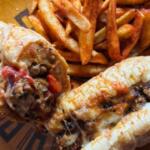 Plate with two stuffed chicken drumsticks with melted cheese and peppers, paired with seasoned French fries on a yellow plate.