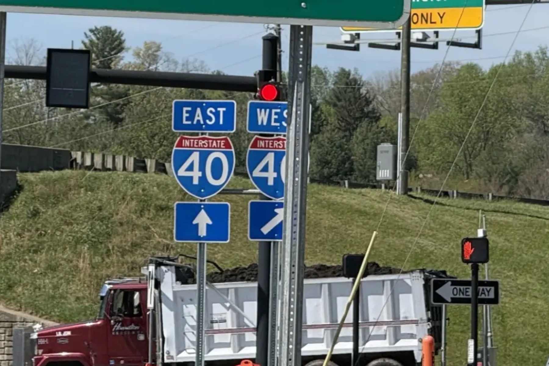 Interstate 40 east and west signs with construction trucks in the background, indicating a highway junction under work.