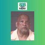 Mugshot portrait of an older man wearing an orange-and-white shirt, set against a gray background with 828 News Now branding above on a teal-green gradient.