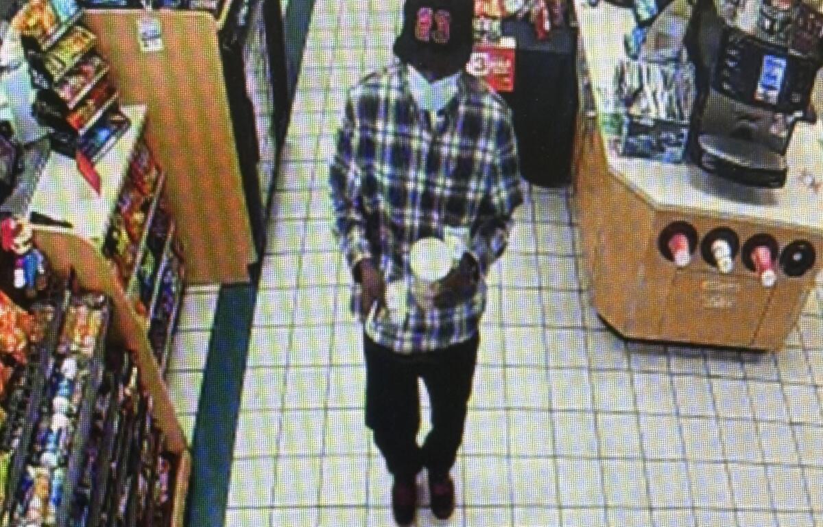 Person wearing a plaid shirt walking down an aisle in a grocery store, shelves stocked with products on the left.