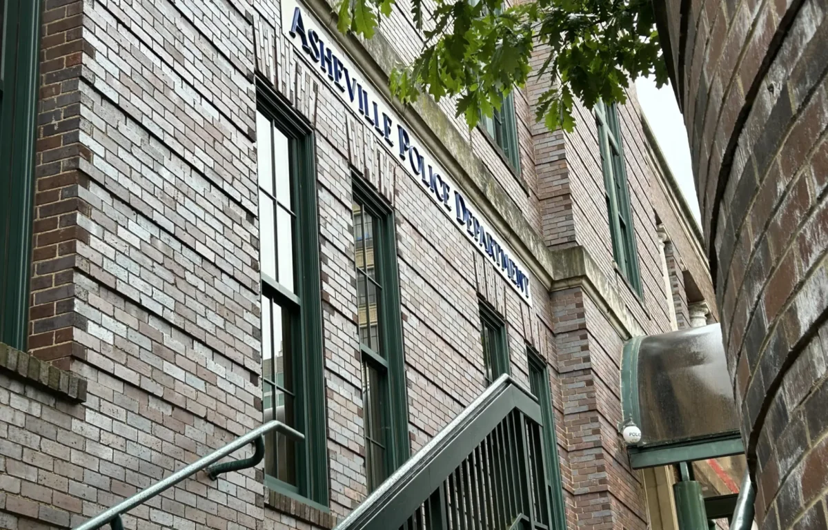 Brick building exterior with green-framed windows and an exterior metal stair railing along a narrow alley. (Informative)