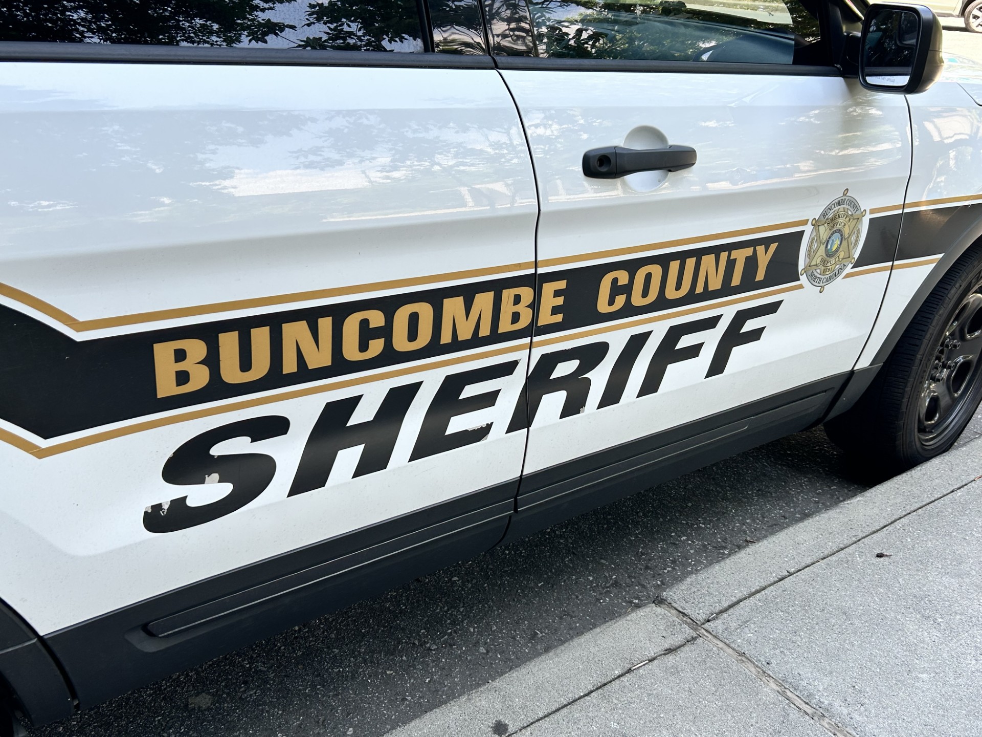 Side view of a Buncombe County Sheriff's Office patrol SUV with emblem and gold stripe on the door edge