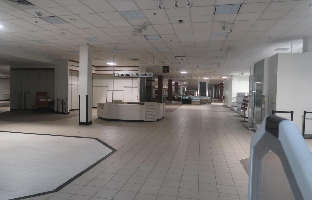 Empty department store interior with a curved white service counter and a 'Customer Service' sign in the distance.