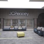 Seating lounge in a mall in front of a JC Penney storefront with gray couches and small tables with flowers.