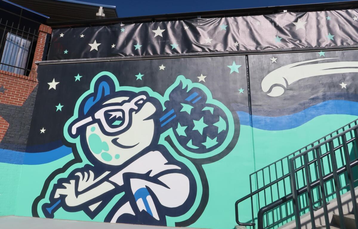 Cartoon astronaut floating among stars on a mural, with teal and blue waves and a metal railing in the foreground.
