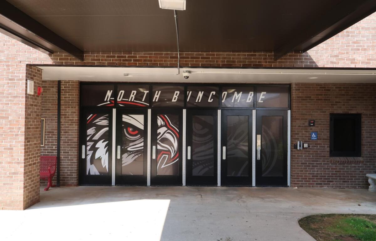 Entrance glass doors to a brick building, decorated with a bold black-red-white animal graphic and large lettering above.