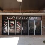 Entrance glass doors to a brick building, decorated with a bold black-red-white animal graphic and large lettering above.