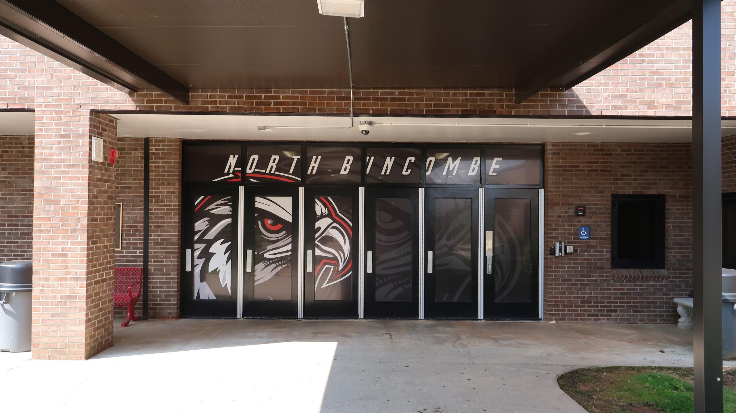 Entrance glass doors to a brick building, decorated with a bold black-red-white animal graphic and large lettering above.