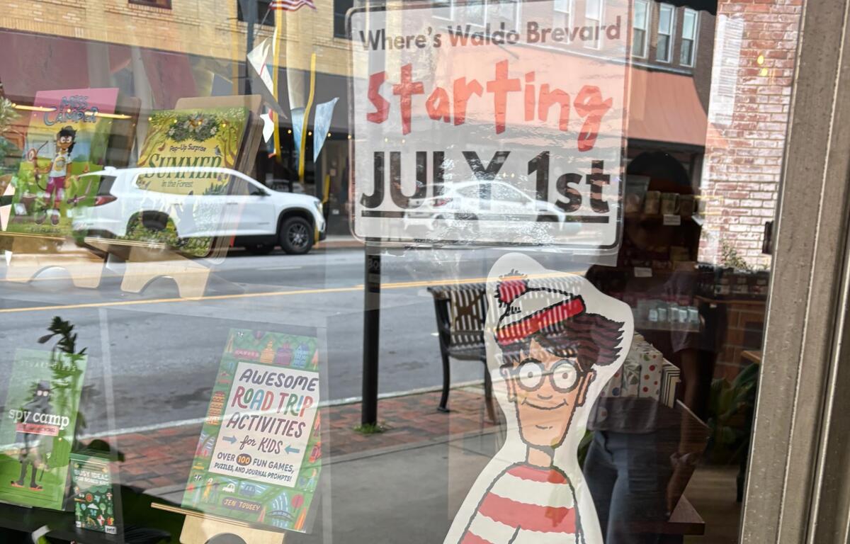Storefront window with a large 'Starting July 1st' sign and colorful kids' posters visible through the glass.
