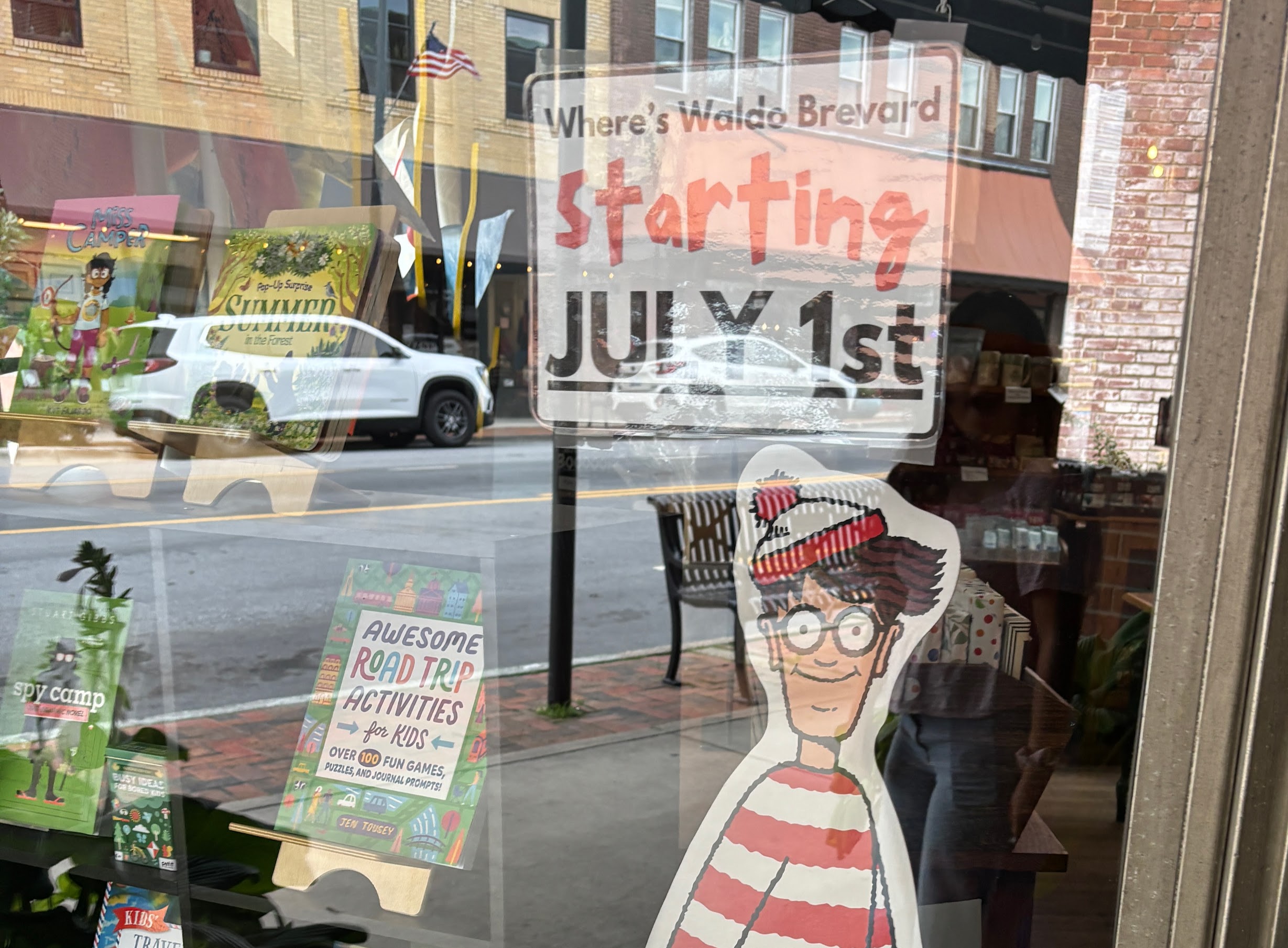 Storefront window with a large 'Starting July 1st' sign and colorful kids' posters visible through the glass.