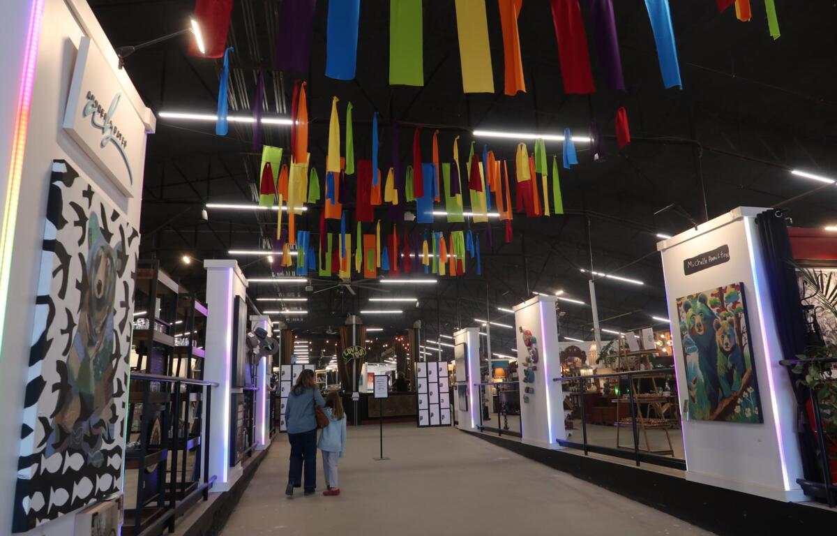 Indoor exhibition hall with booths and multicolored fabric ribbons hanging from the ceiling overhead.