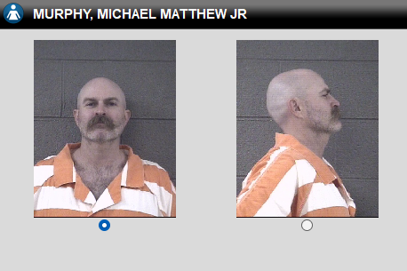 Two mugshots of a bald man with a mustache in an orange jumpsuit, shown from front and side against a gray wall.