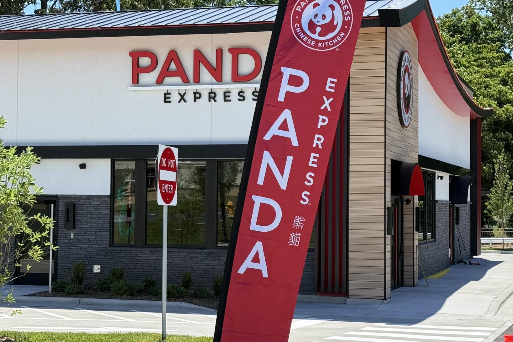 Exterior of a Panda Express restaurant with a large red vertical banner in the foreground and a 'Do Not Enter' sign nearby.