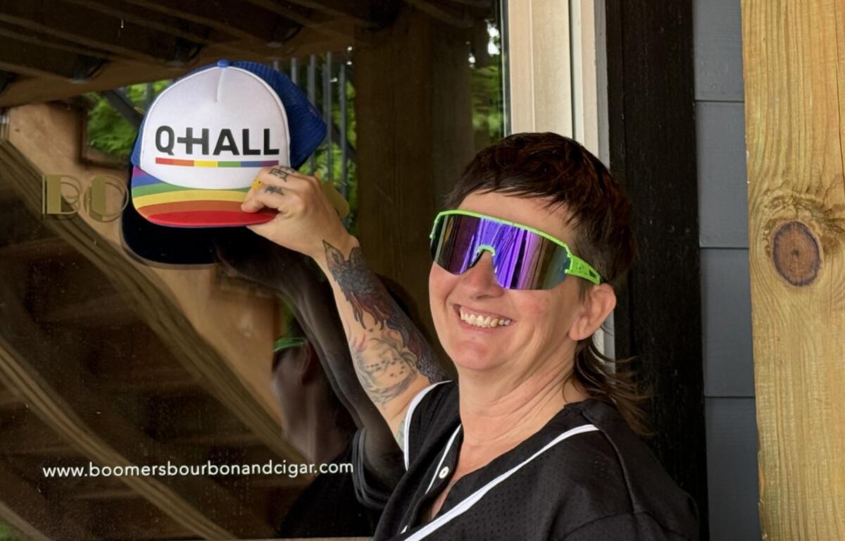 JJ Pope stands at the entrance of the future Q-Hall in downtown Asheville, covering the former Boomers logo with her hat. Pope hopes to open Asheville's first women's sports bar later this year.