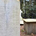 Stone tombstone with an engraved poem in a cemetery; the visible lines begin 'How shall I speak of Thee...' with trees in the background.