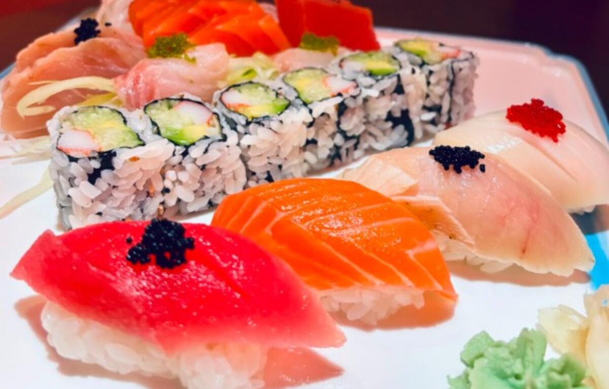 Assorted sushi platter with nigiri (salmon, tuna, white fish) and cucumber–avocado maki rolls, wasabi on the side.