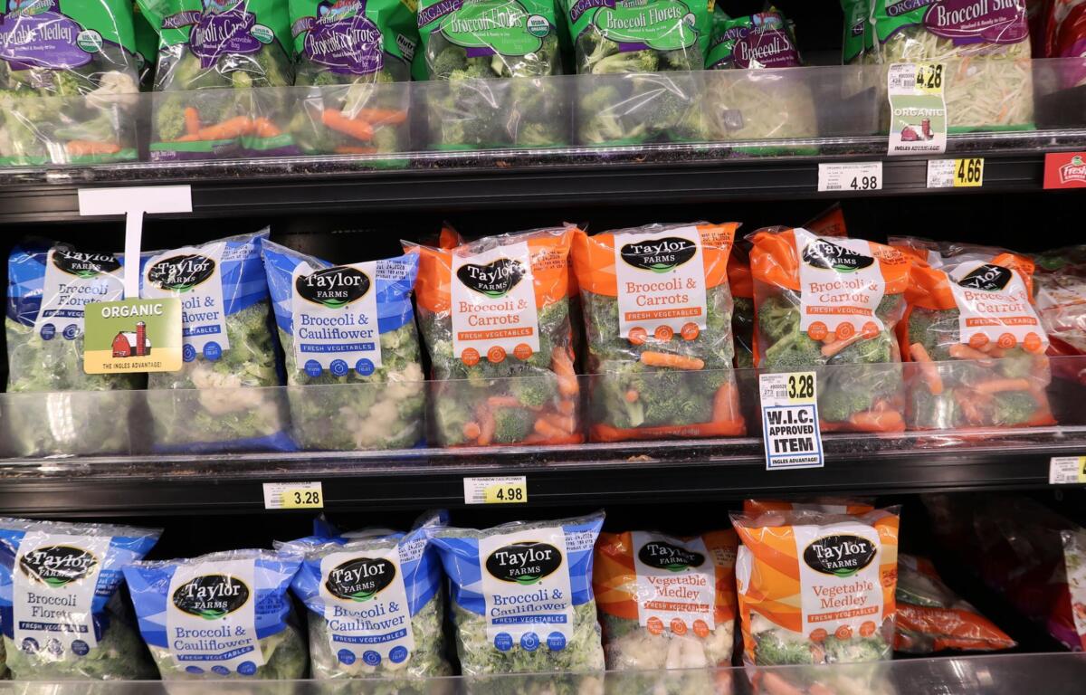 Shelf of Taylor Farms frozen vegetables: broccoli and cauliflower, and broccoli & carrots bags visible on display.