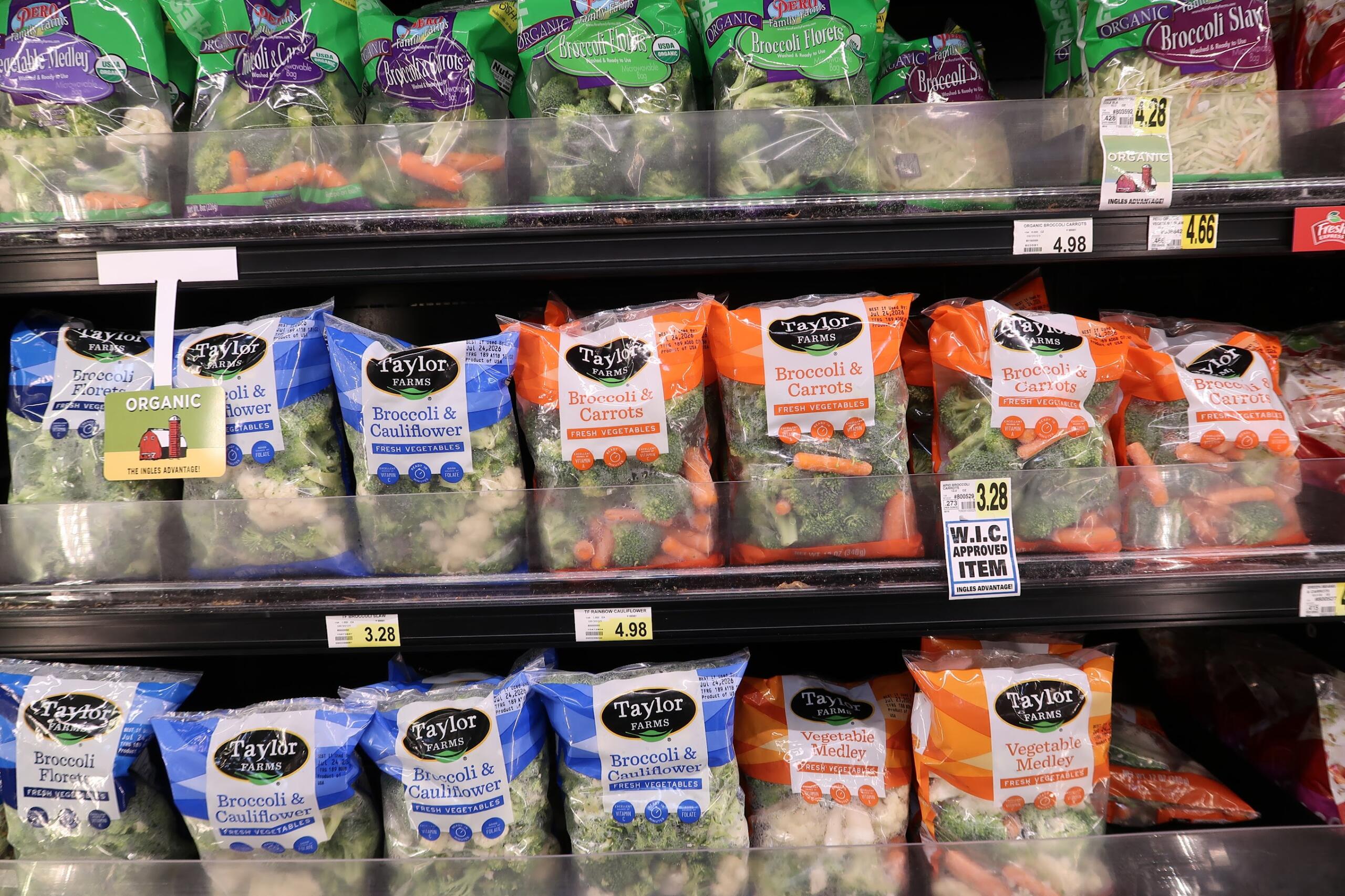 Shelf of Taylor Farms frozen vegetables: broccoli and cauliflower, and broccoli & carrots bags visible on display.