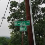 Green street signs for Hi-Alta Ave and Deerview Rd mounted on a wooden utility pole among trees and power lines.