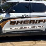 White sheriff SUV with orange/black graphics reading Buncombe County Sheriff; badge emblem on front door.
