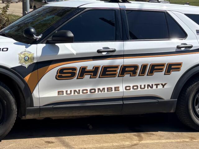 White sheriff SUV with orange/black graphics reading Buncombe County Sheriff; badge emblem on front door.