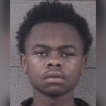 Mugshot photo of a young Black man facing the camera with a neutral expression, against a gray background.