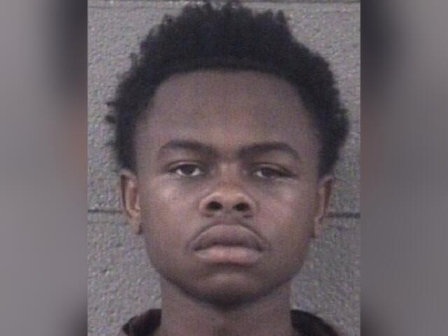 Mugshot photo of a young Black man facing the camera with a neutral expression, against a gray background.