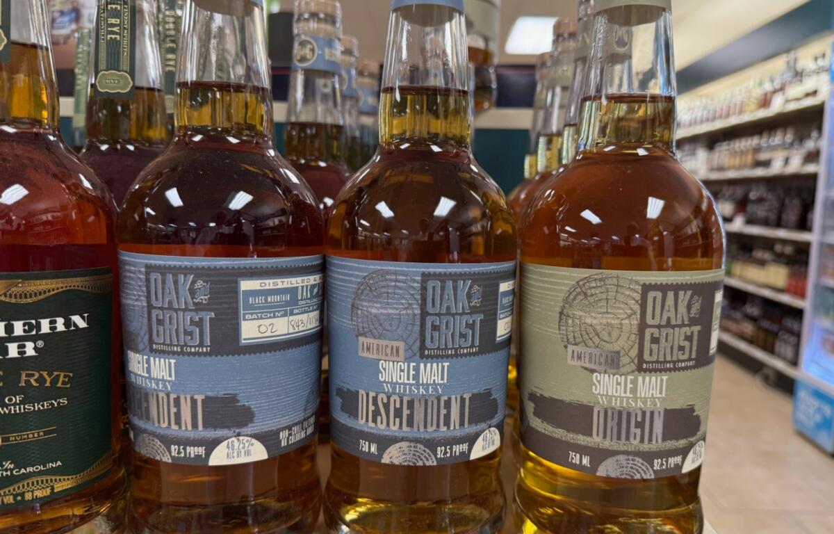 Three Oak Grist single malt whiskeys on a store shelf, labels show Descendent and Original variants.
