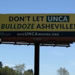 A "Save the Woods" billboard stands along Future I-26 in Asheville, highlighting community opposition to potential development of UNC Asheville's South Campus woods.