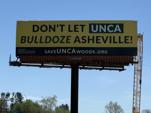 A "Save the Woods" billboard stands along Future I-26 in Asheville, highlighting community opposition to potential development of UNC Asheville's South Campus woods.