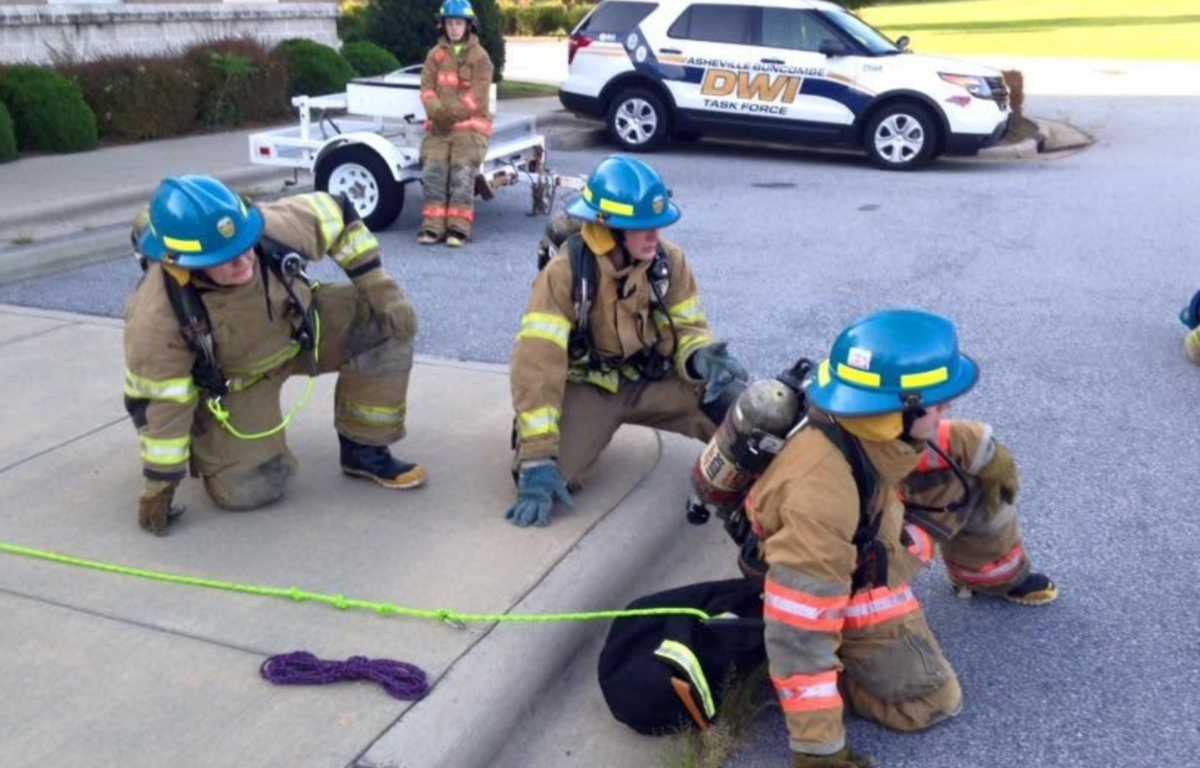 Participants in past Asheville Fire Department Explorer programs take part in hands-on firefighting training.
