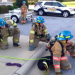 Participants in past Asheville Fire Department Explorer programs take part in hands-on firefighting training.