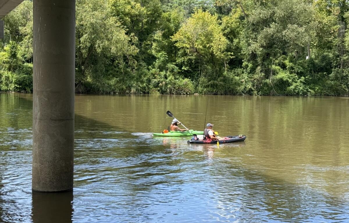 Two fishermen paddle beneath the Craven Street Bridge over the French Broad River as construction continues on the I-26 Connector project in Asheville.
