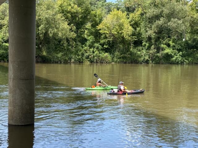 Two fishermen paddle beneath the Craven Street Bridge over the French Broad River as construction continues on the I-26 Connector project in Asheville.