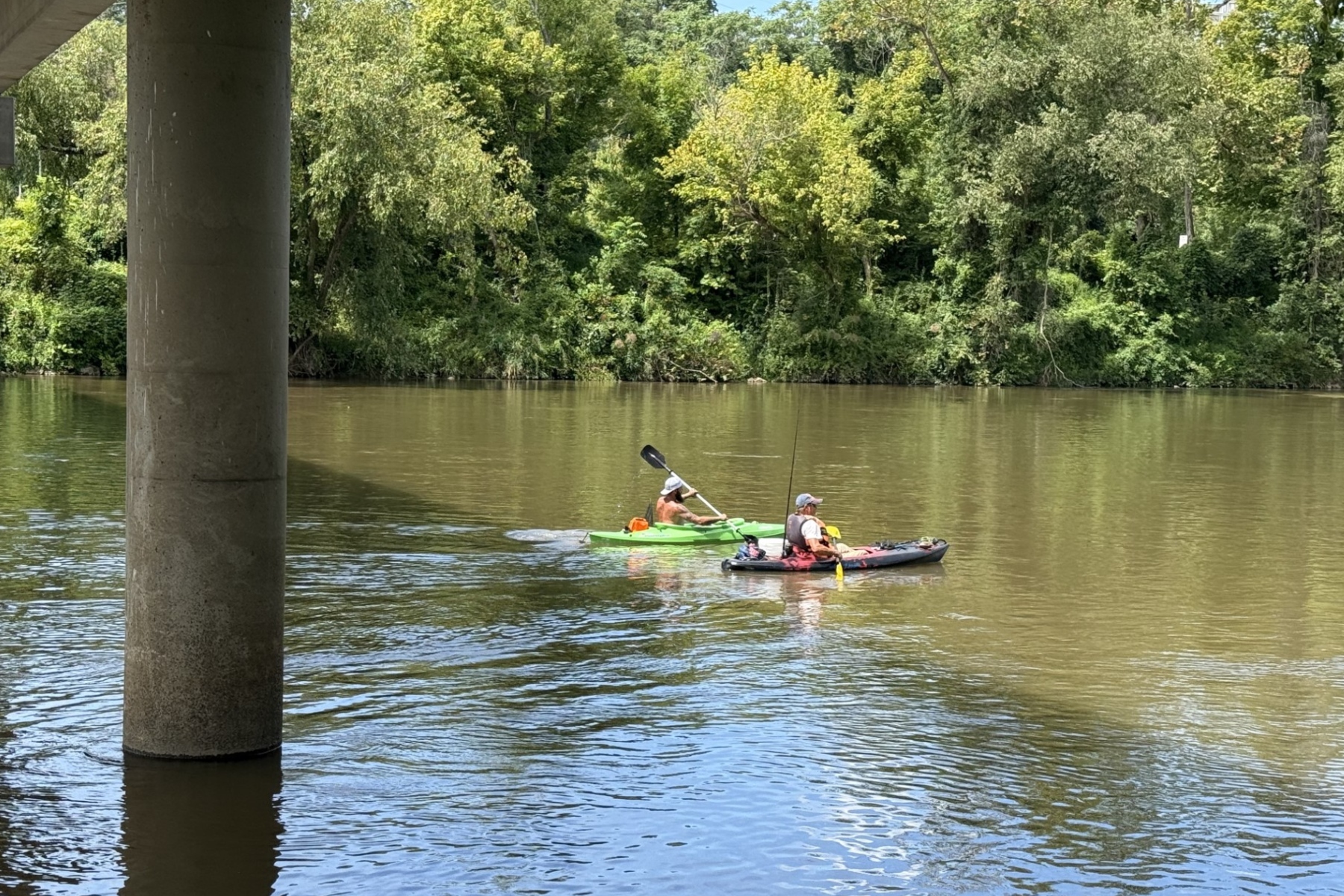 Two fishermen paddle beneath the Craven Street Bridge over the French Broad River as construction continues on the I-26 Connector project in Asheville.