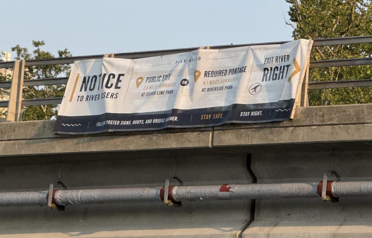 A sign on the Craven Street Bridge provides directions for river users as construction begins in the French Broad River for the I-26 Connector project.