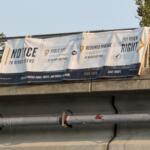 A sign on the Craven Street Bridge provides directions for river users as construction begins in the French Broad River for the I-26 Connector project.