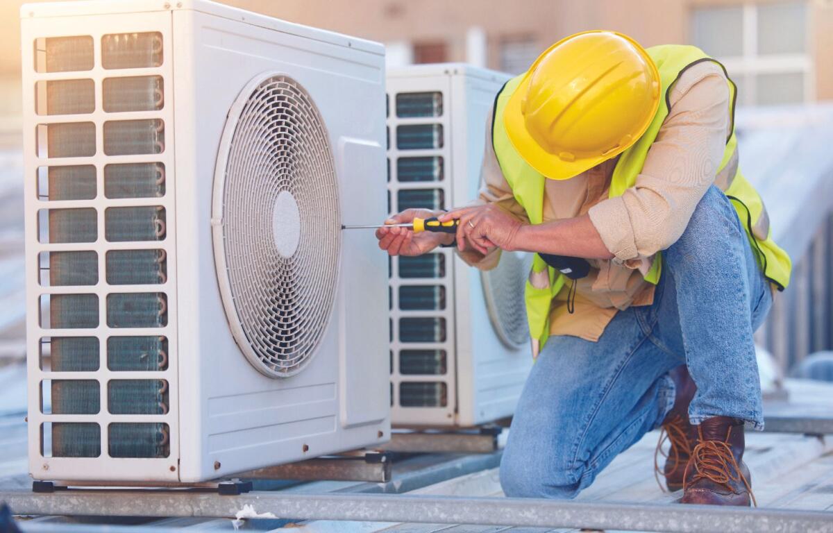 HVAC technician performing maintenance on an outdoor air conditioning unit.