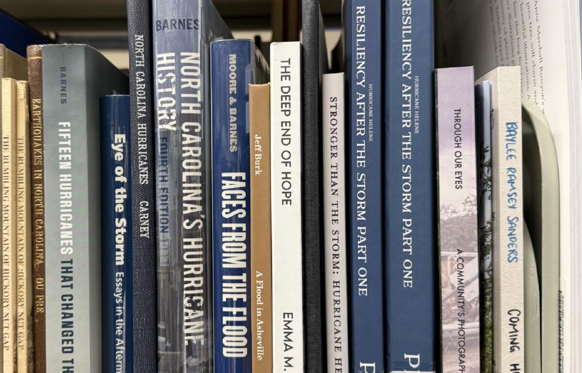 Books about Tropical Storm Helene and its impact on Western North Carolina line a shelf in the Special Collections area at Pack Memorial Library in Asheville.