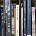 Books about Tropical Storm Helene and its impact on Western North Carolina line a shelf in the Special Collections area at Pack Memorial Library in Asheville.