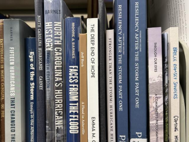 Books about Tropical Storm Helene and its impact on Western North Carolina line a shelf in the Special Collections area at Pack Memorial Library in Asheville.