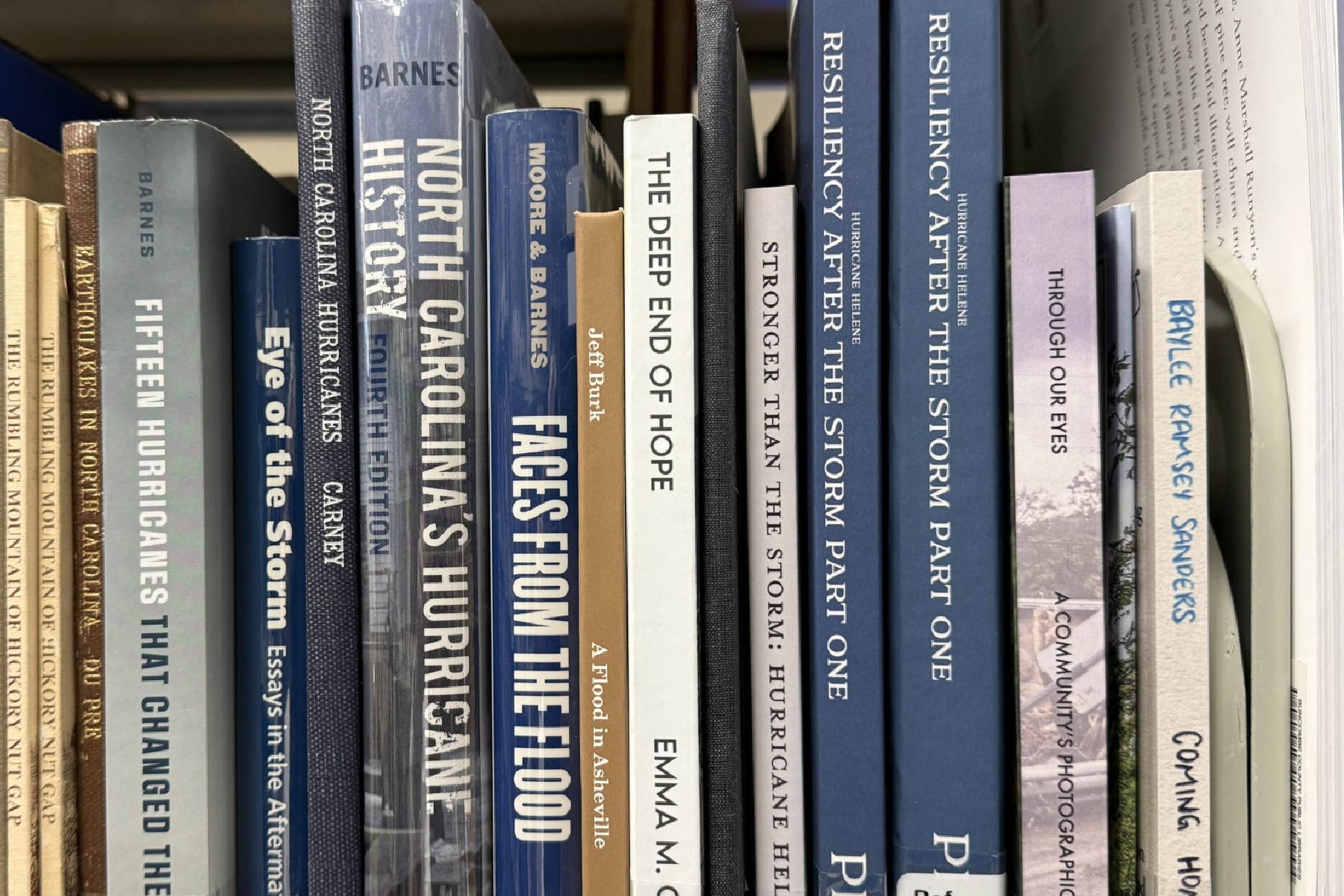 Books about Tropical Storm Helene and its impact on Western North Carolina line a shelf in the Special Collections area at Pack Memorial Library in Asheville.