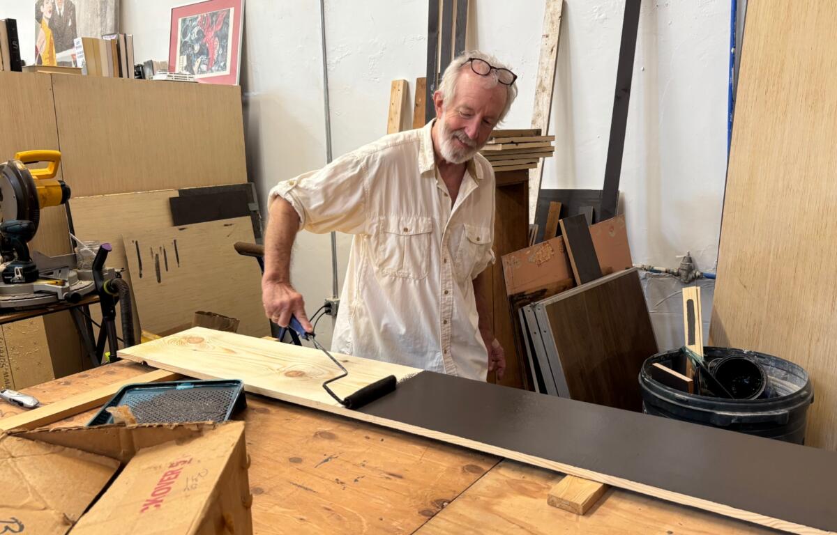 French Broad Exchange owner Jamey Smith paints bookshelves in the back of his store.