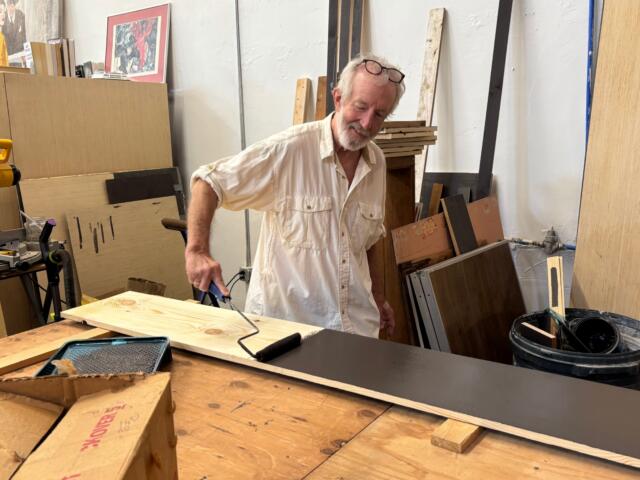 French Broad Exchange owner Jamey Smith paints bookshelves in the back of his store.